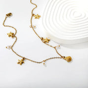 joya con perla delicada y dijes de estrellas de mar doradas 